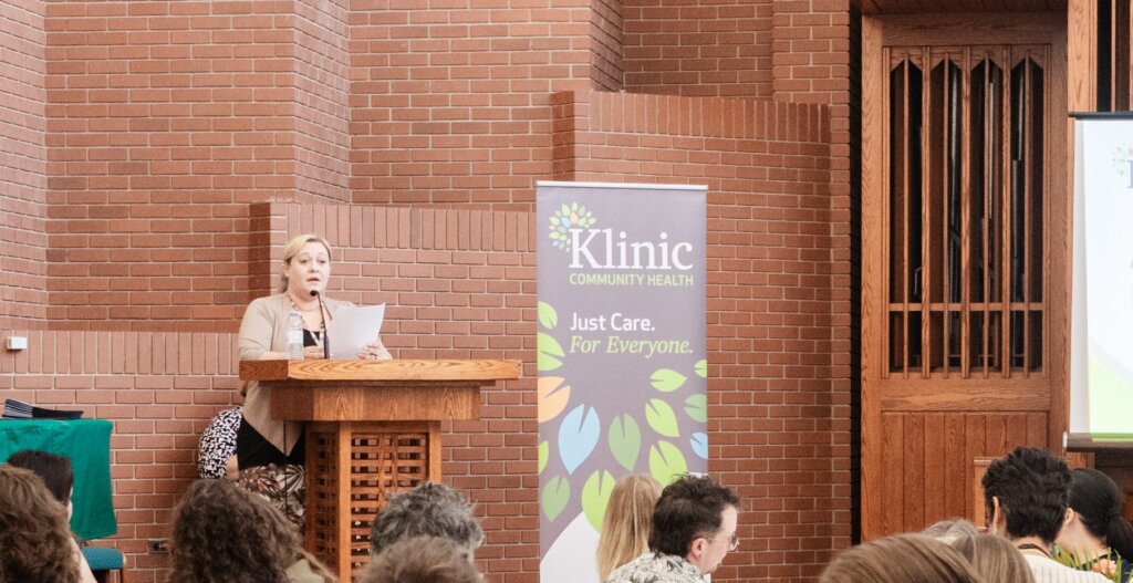 Kathy speaks at an AGM in front of a podium