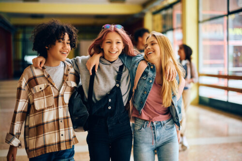Three teens walk down a hallway.