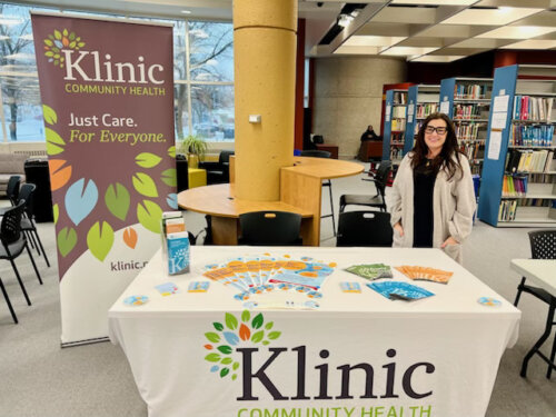Klinic staff stand at table that is labelled with Klinic's logo.