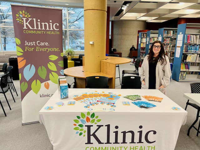Klinic staff stand at table that is labelled with Klinic's logo.