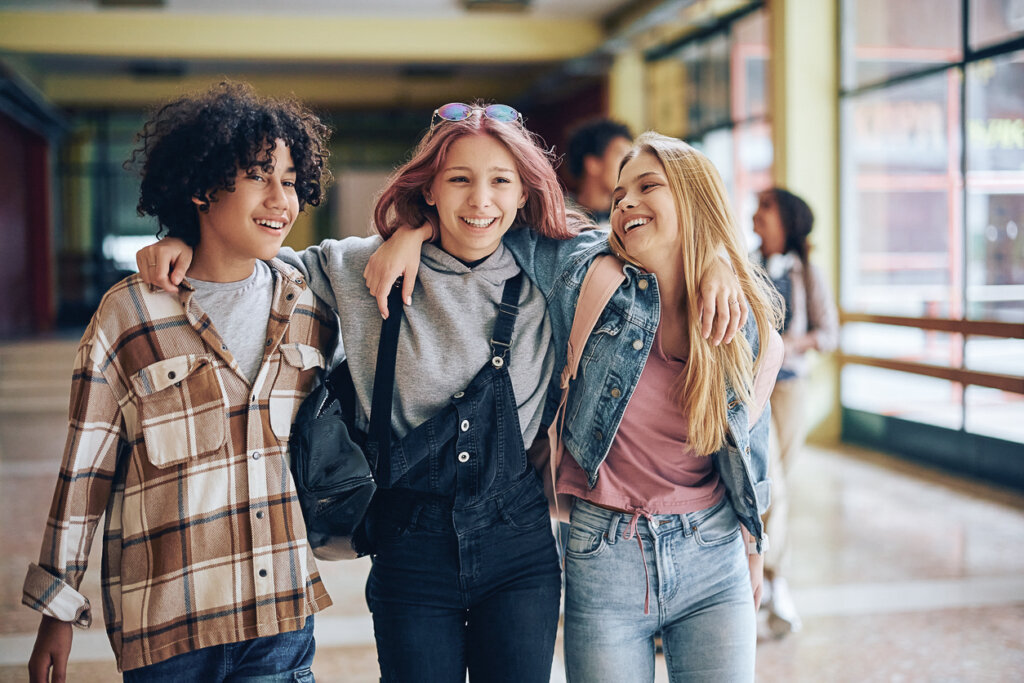 Three teens walk down a hallway.